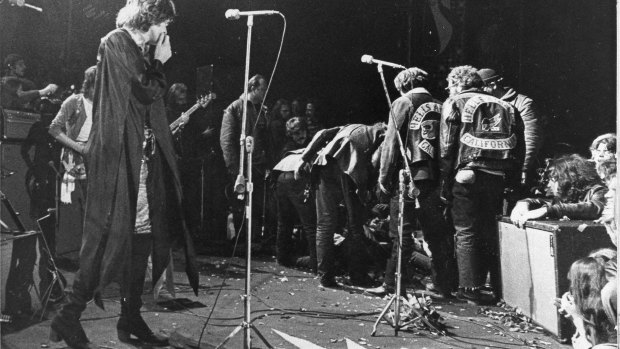 Mick Jagger looks on as the Hells Angels drag an unidentified person onstage at the Altamont  rock festival, California, Dec 6, 1969.