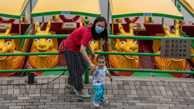 A woman and her child walk in a park in Beijing. China has been doling out tax and housing credits, educational benefits and cash to encourage women to have more children.