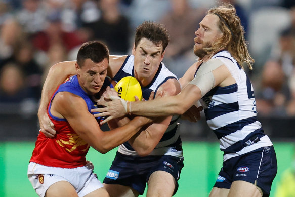 Hugh McCluggage of the Lions is tackled by Jeremy Cameron and Cameron Guthrie.