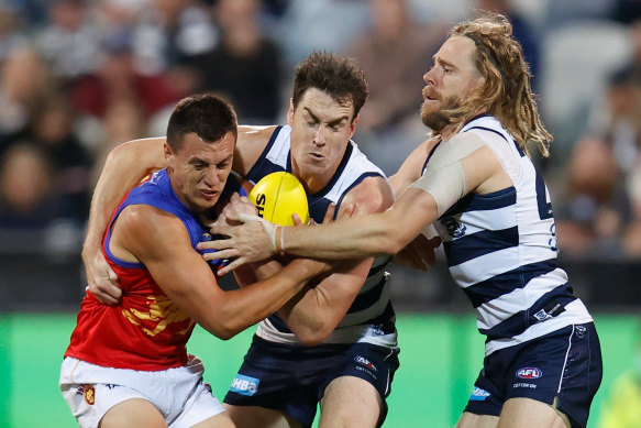 Hugh McCluggage of the Lions is tackled by Jeremy Cameron and Cameron Guthrie.