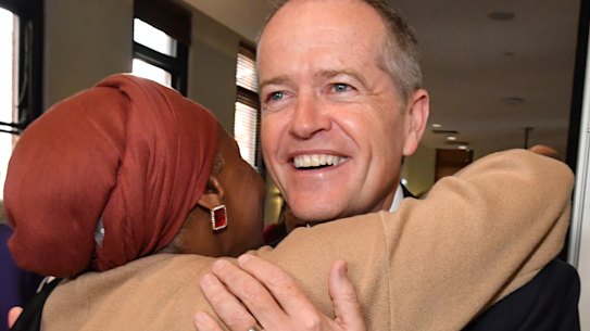 Opposition Leader Bill Shorten hugs Hawa Del as his wife Chloe Shorten  looks on during the launch of Labor's policy to lift the equality of Australian women at the Queen Victoria Women's Centre in Melbourne on Friday. 