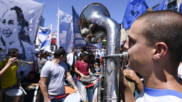 Musicians play as tens of thousands march against the economic policies of Argentina's government in Buenos Aires, with some holding banners picturing Evita, left.