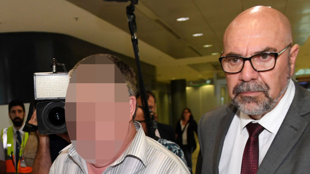 A man (left) extradited from Victoria in connection with the 1970 abduction and murder of Cheryl Grimmer is escorted by detective Frank Sanvitale in 2017.