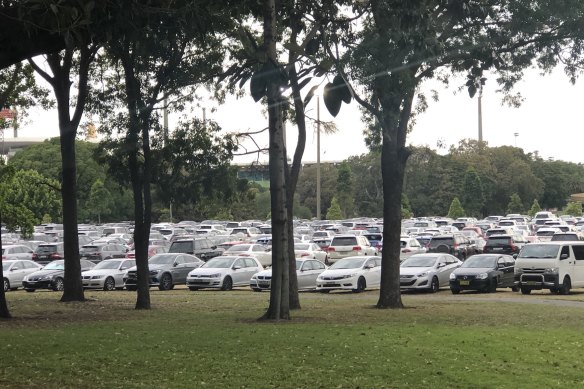 Cars parked on fields near Kippax Lake at Moore Park during an event.