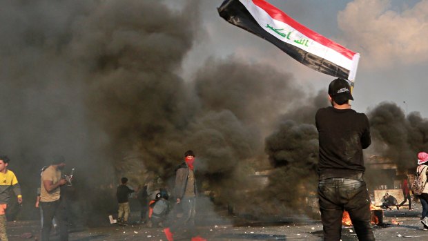 A protester waves the national flag during clashes with security forces in central Baghdad.