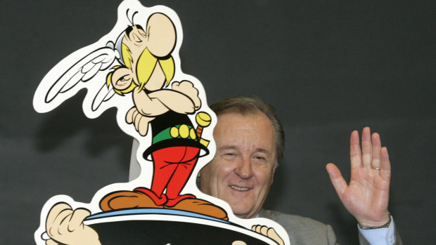 French author and illustrator Albert Uderzo waves from behind a cardboard cutout showing his comic heroes Asterix and Obelix at the 57th Frankfurt Book Fair, 2005.
