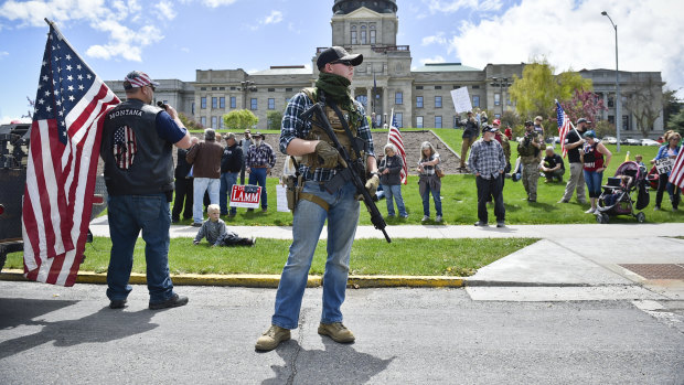 A protester with a gun and others stand outside the Montana State Capitol in Helena, Montana last year. 