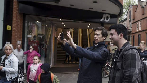 Rory Stewart, centre, a candidate for prime minister, takes a selfie with a supporter as he campaigns in Wigan, England.