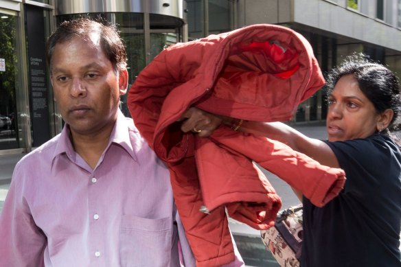 Kandasamy (left) and Kumuthini Kannan try to conceal their faces outside court in 2017.