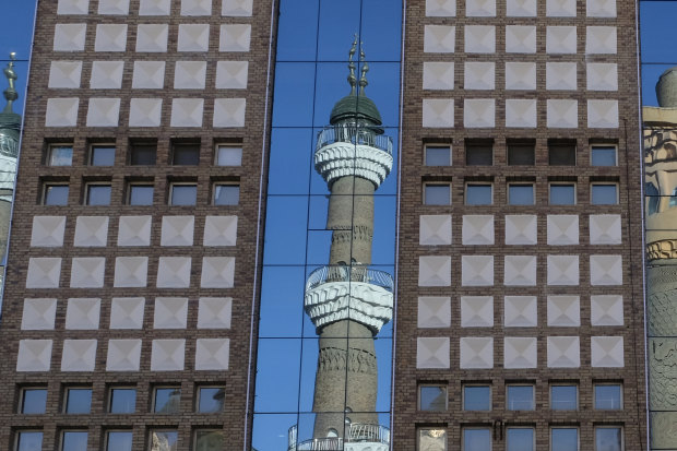 The minarets of the Urumqi International Grand Bazaar Mosque are reflected on nearby building. Taking pictures of mosques, government buildings, and police is prohibited in Urumqi, a local police officer tells us.