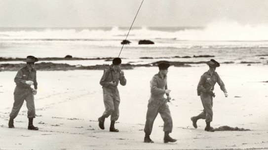 An army search party equipped with two-way radio look for Harold Holt on Cheviot Beach.
