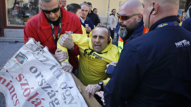 Security personnel drag a man holding a banner that reads "There is no freedom after speech in this country" ahead of the final electoral rally of Prime Minister Viktor Orban's Fidesz party in, Szekesfehervar, Hungary, on Friday.