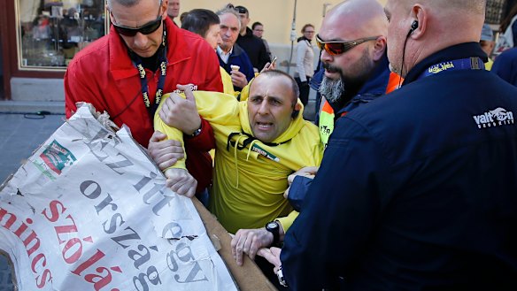 Security personnel drag a man holding a banner that reads "There is no freedom after speech in this country" ahead of the final electoral rally of Prime Minister Viktor Orban's Fidesz party in, Szekesfehervar, Hungary, on Friday.