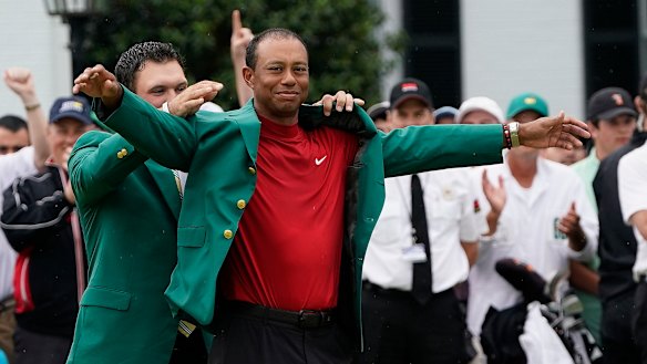Glory days: Last year's Masters winner Patrick Reed helps Tiger Woods put on the famous green jacket.