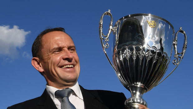 Trainer Chris Waller holds the trophy after jockey James McDonald rode The Autumn Sun to victory.