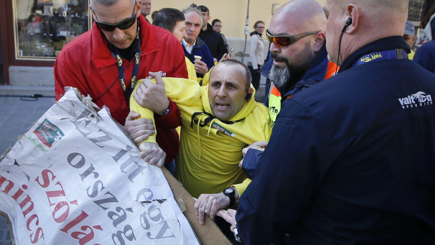 Security personnel drag a man holding a banner that reads "There is no freedom after speech in this country" ahead of the final electoral rally of Prime Minister Viktor Orban's Fidesz party in, Szekesfehervar, Hungary, on Friday.