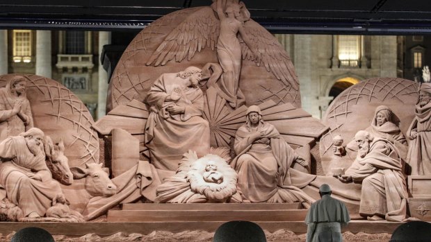 Pope Francis prays in front of a nativity scene.