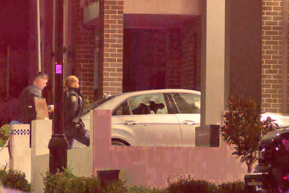 Police officers inspect a car in which a man was shot in Elizabeth Hills on Monday.