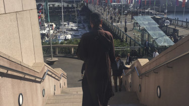 A fake Buddhist monk approaches people for money in Darling Harbour.