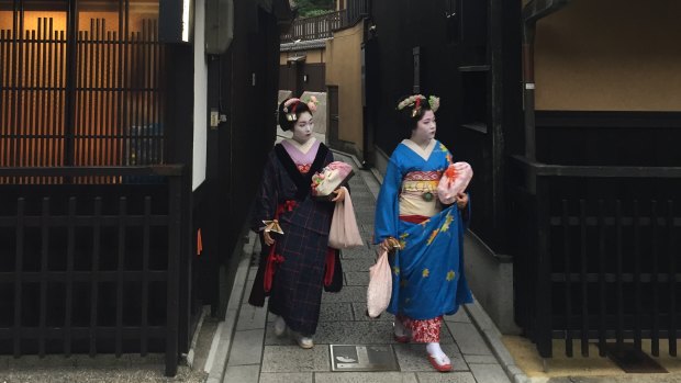 The two geisha leave a laneway in Kyoto.