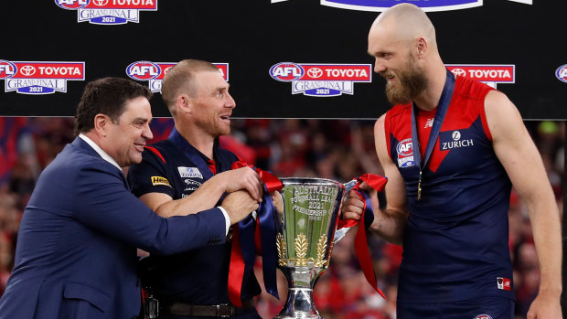 Garry Lyon presents the premiership cup to Simon Goodwin and Max Gawn.