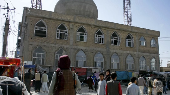 This frame from a video,shows a Taliban fighter standing guard outside the site of a bomb explosion inside a mosque in Mazar-i-Sharif province.