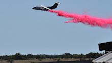 A tanker aircraft dumps fire retardant on a field southwest of Salado, Texas, after a military helicopter crashed and sparked a grass fire.