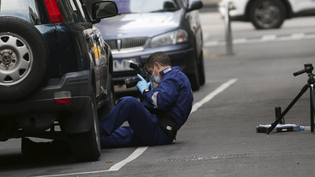 A forensics officer takes photos of a car parked in Anthony Street.