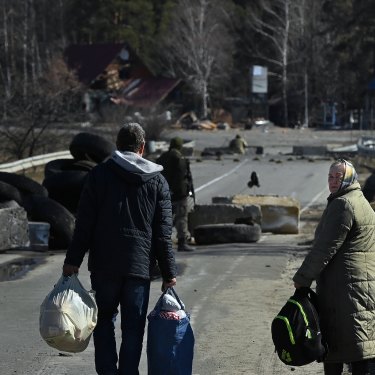 Locals walk towards their home over a destroyed bridge laid with anti tank mines. East of Kyiv, Ukraine.