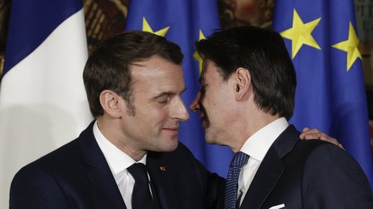 French President Emmanuel Macron puts his arm around Italian Prime Minister Giuseppe Conte as he shakes his hand and kisses him on both cheeks in Naples on February 27.