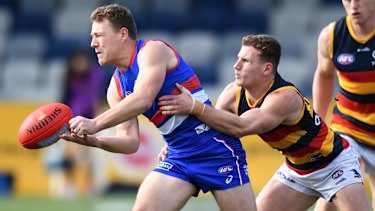 Jack Macrae is tackled as he gets a handball away.