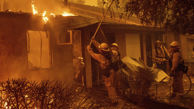 Firefighters work to keep flames from spreading through the Shadowbrook apartment complex as a wildfire burns through Paradise, California.