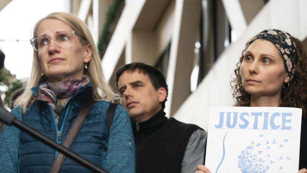 Sarah Kuhnen is teary-eyed and Jenelle Masterson holds a sign reading "Justice for Justine" outside the courtroom. 