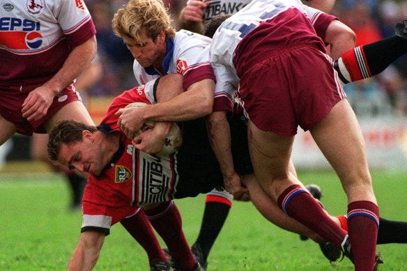North Sydney enforcer Billy Moore is driven into the Brookvale turf by Manly’s Des Hasler in 1995.