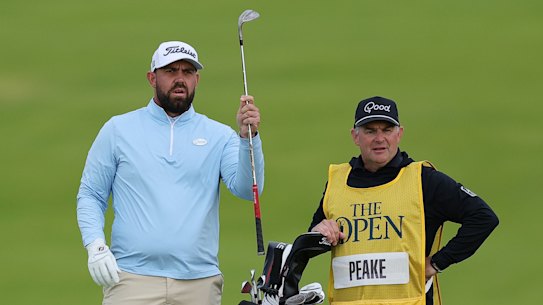 Ryan Peake of Australia selects a club from his bag as he stands with his caddie on the first hole during day one of The 153rd Open Championship at Royal Portrush Golf Club in Ireland.