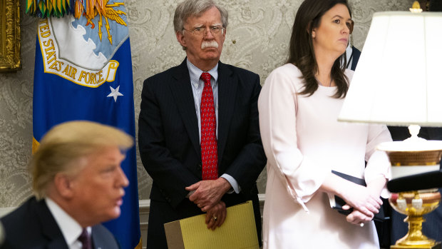 US President Donald Trump (left) and National Security Adviser John Bolton with Sarah Sanders in the Oval Office.