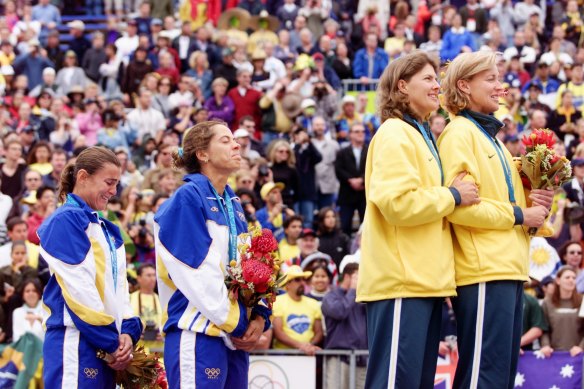 Natalie Cook and Kerri Pottharst bask in Olympic glory as their vanquished Brazilian opponents cry.