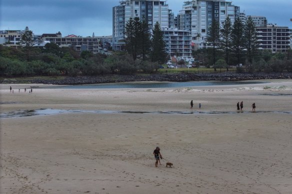 People walking across the old Caloundra Bar, off the Bulcock and Happy Valley beaches, during low tide, in March this year.