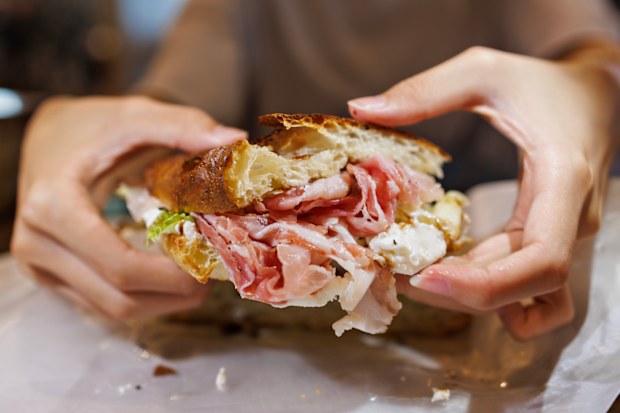 Close-up of an Italian-style focaccia sandwich filled with ham, cheese, and lettuce