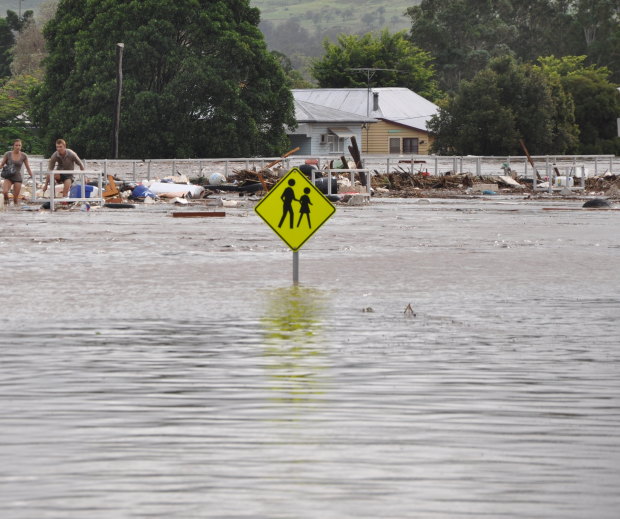 A young Toowoomba couple desperately cross the Grantham rail line as floodwaters rise on January 10, 2011.