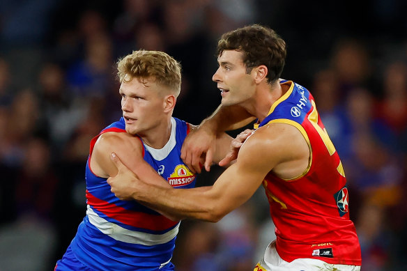 Adam Treloar of the Bulldogs and Josh Dunkley of the Lions compete for the ball.