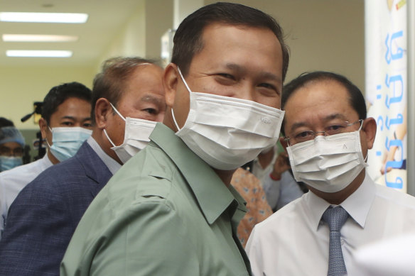 Cambodia’s Lieutenant General Hun Manet, foreground, a son of Prime Minister Hun Sen, smiles after receiving a COVID vaccine donated by China.