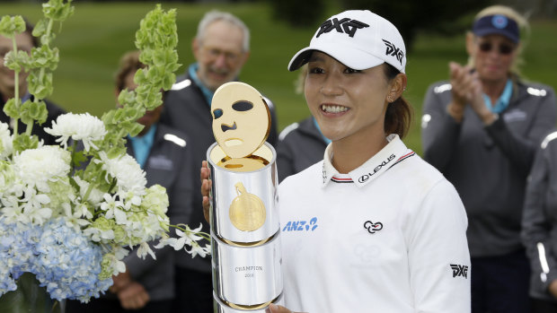 Lydia Ko, of New Zealand, poses with her trophy on 18th green.
