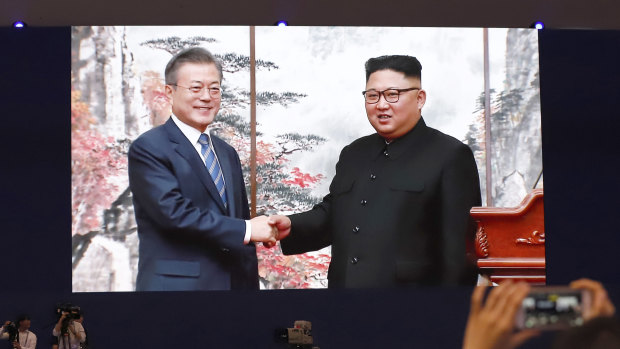 Members of media and volunteers watch a huge screen showing South Korean President Moon Jae-in, left, shake hands with North Korean leader Kim Jong-un after a joint press conference in Pyongyang, North Korea.