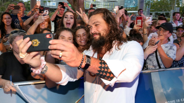 Jason Momoa takes selfies with the crowd behind him at the Australian  premiere of Aquaman on the Gold Coast on Tuesday.