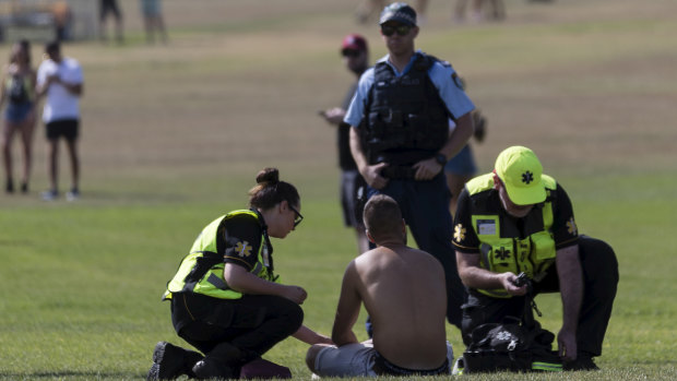 A man receives medical attention outside the Electric Gardens dance music festival at Centennial Park on Saturday.