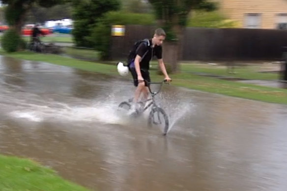 A cyclist rides through a flooded street in Corio, near Geelong, this afternoon.