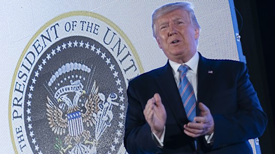 President Donald Trump stands in front of a doctored presidential seal on stage at the Turning Point USA student action summit.