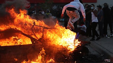 A man jumps off a burning car in a Target carpark in Minneapolis.