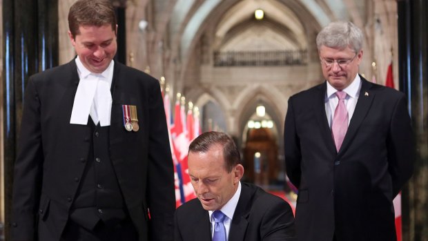 Then-Australian prime minister Tony Abbott signs the guest book as then-Canadian prime minister  Stephen Harper, right, and then Speaker of the House of Commons Andrew Scheer watch on, at Parliament Hill in Ottawa, Ontario, in June 2014.